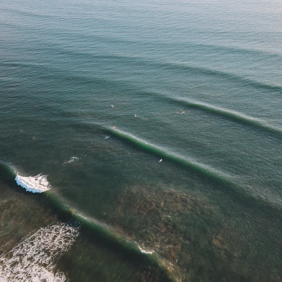 Aerial view of clean waves peeling along the El Salvador coastline with a paddle surfer riding one