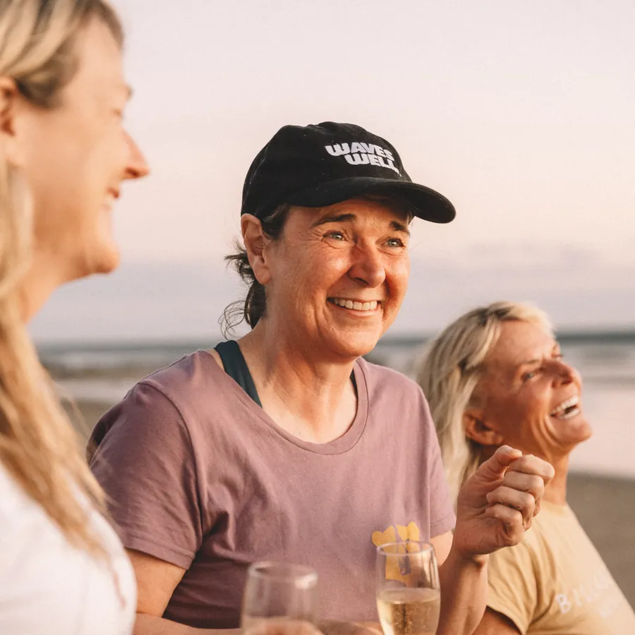 Two guests laughing together over a drink at sunset