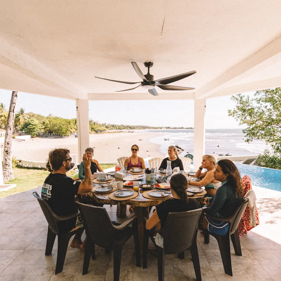 The group having dinner together at the long table beside the pool
